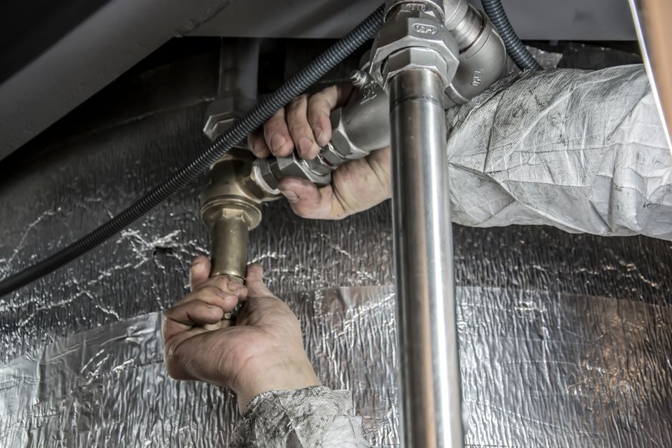 Plumber tightening a supply line under a fixture